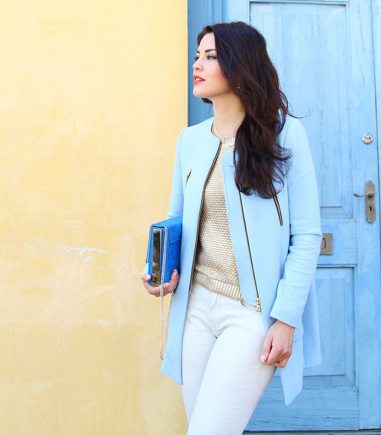 Brunette girl posing in the street with a pastel blue jacket and a klein blue bag