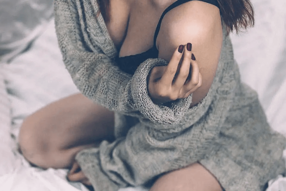 Mujer rascándose la piel por culpa de la ropa